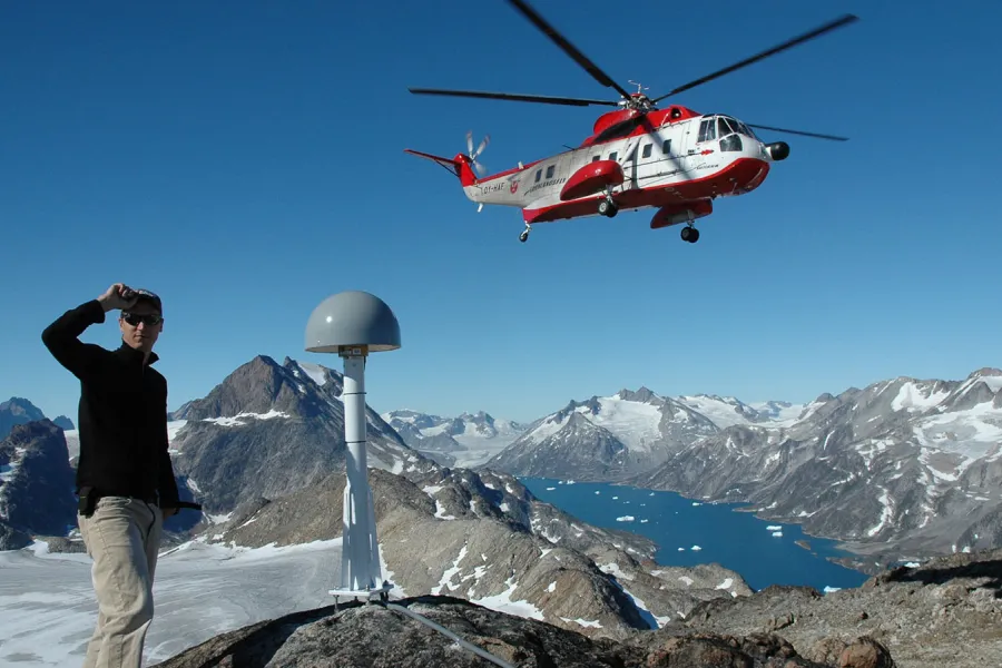 Student next to helicopter on mountain