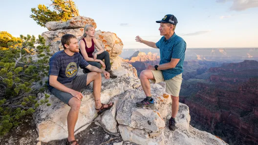 Abe Springer talking to two young adults on top of a canyon