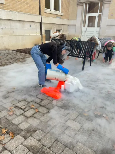 Batoul Saad doing a dry ice activity where she poured dry ice on fruit and then broke it on the floor.