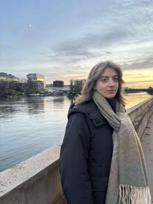 Picture of person wearing coat and scarf standing in front of a river 