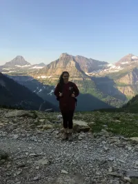 Kara Lamantia stands at top of a mountain and other mountains can be seen behind her